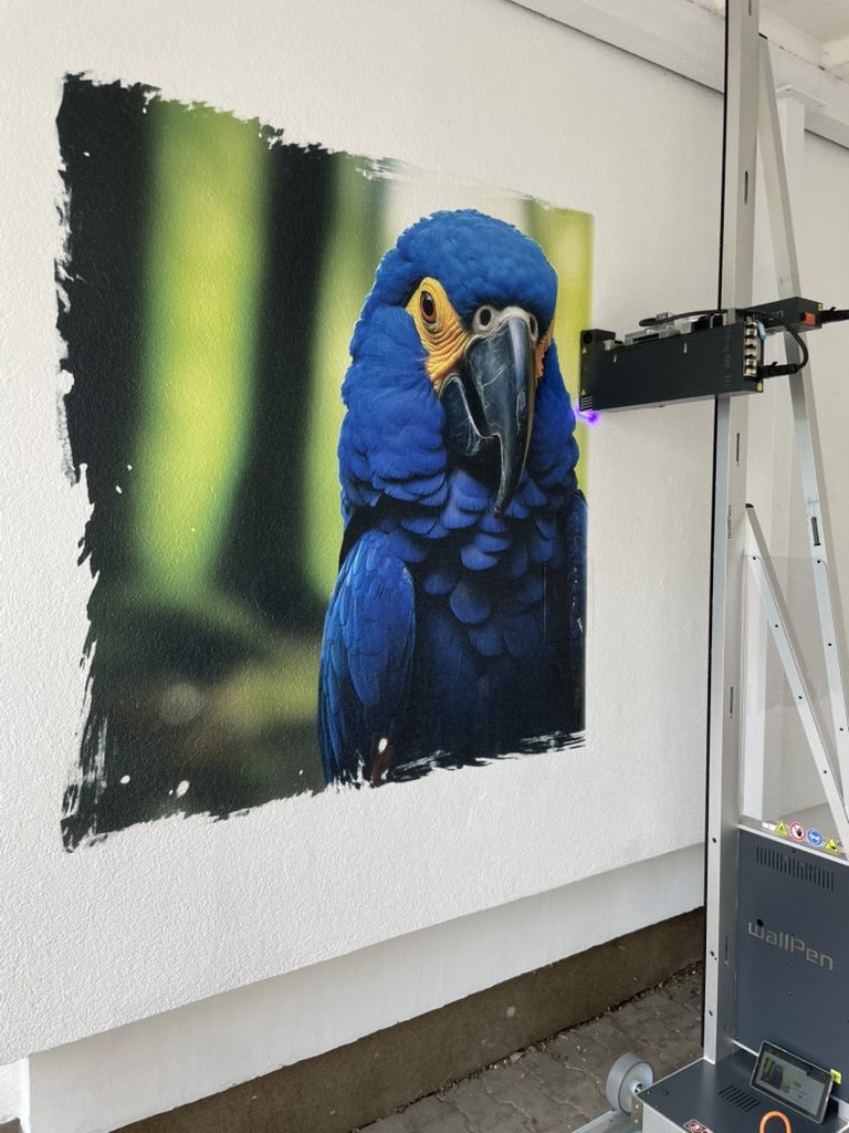 Drukarka ścienna WallPen E2 drukuje niebieską arę na elewacji w Szczecinie