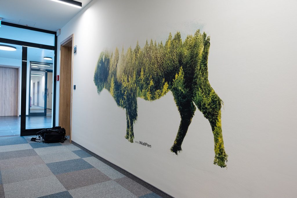 Mural z żubrem utkanym z lasu na ścianie korytarza w biurowcu w Poznaniu – druk UV wallPen
