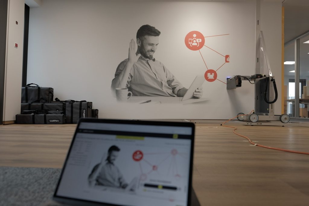 Grafika ścienna w strefie open space w biurowcu w Poznaniu – mężczyzna przy tablecie, druk UV wallPen