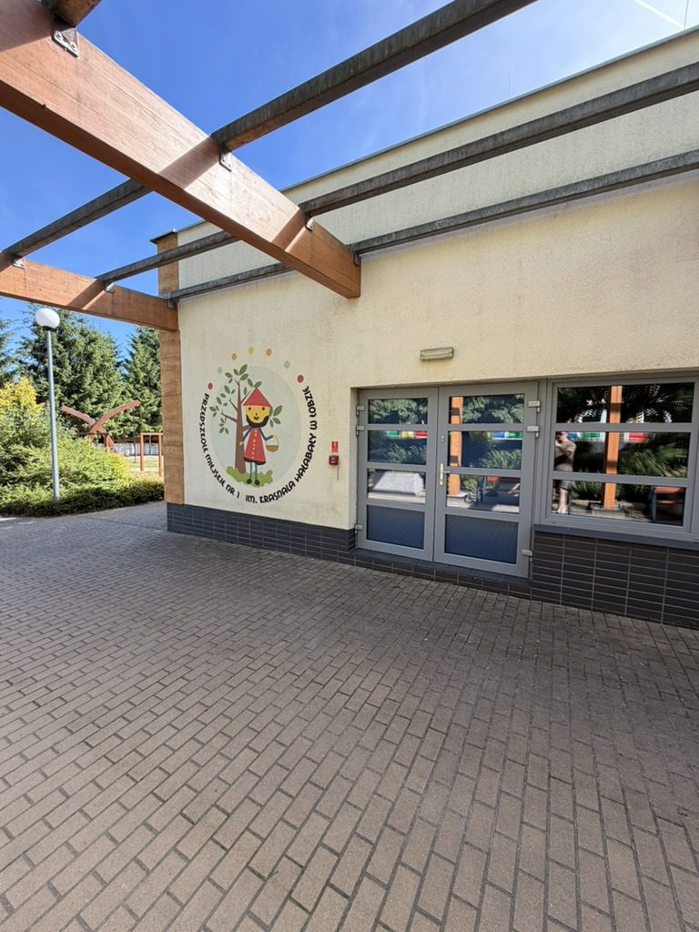 Wejście do przedszkola w Łobzie z widocznym muralem i przeszklonymi drzwiami