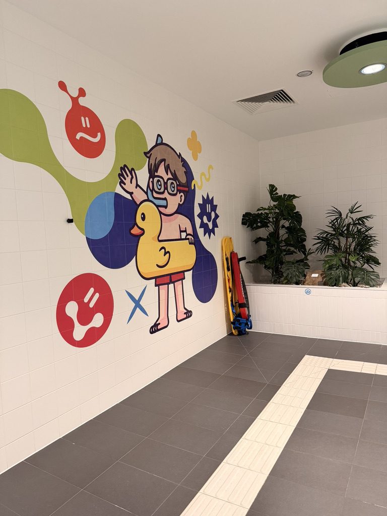 Mural chłopca z gumową kaczuszką na kafelkach w wilgotnej strefie basenowej Fabryki Wody