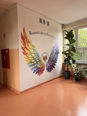 Mural ze skrzydłami w korytarzu SP 4 w Goleniowie – widok z holu